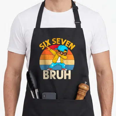 Dabbing number meme apron - Cartoon boy dabbing under arched Six Seven text and above Bruh on striped sun — shown on a black cotton canvas apron against a white background