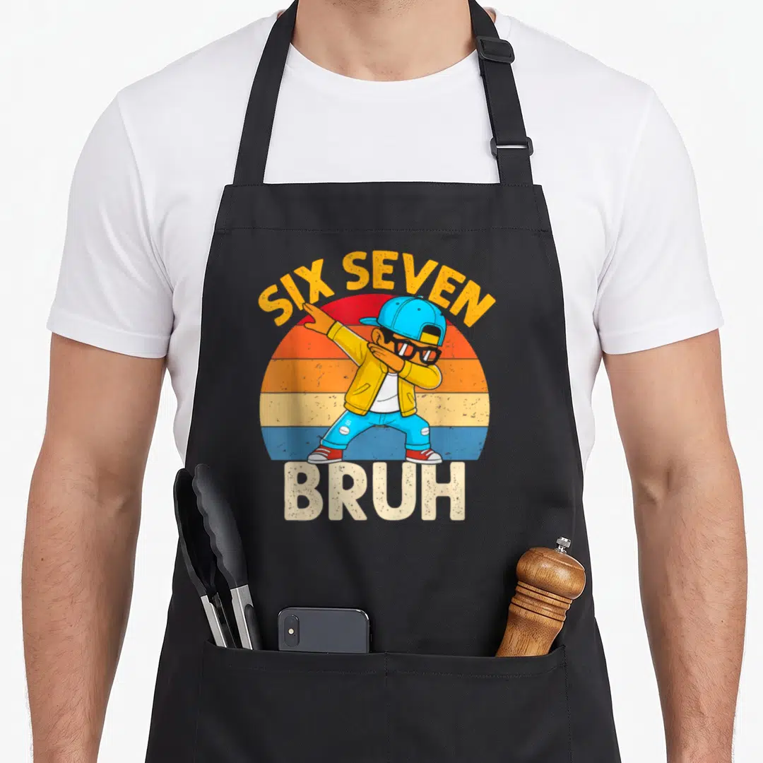 Dabbing number meme apron - Cartoon boy dabbing under arched Six Seven text and above Bruh on striped sun — shown on a black cotton canvas apron against a white background