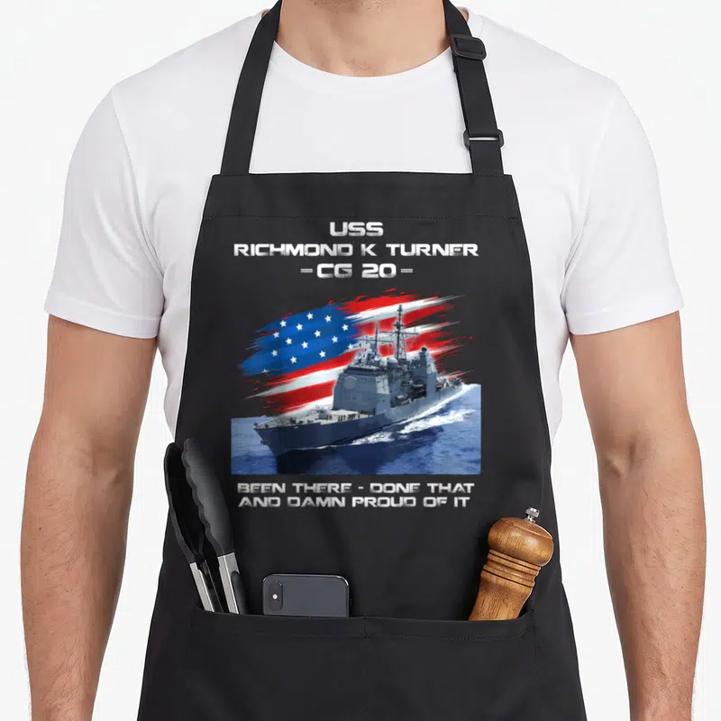 Turner american flag apron - USS Richmond K Turner CG 20 ship with flag and proud service text — shown on a black cotton canvas apron against a white background