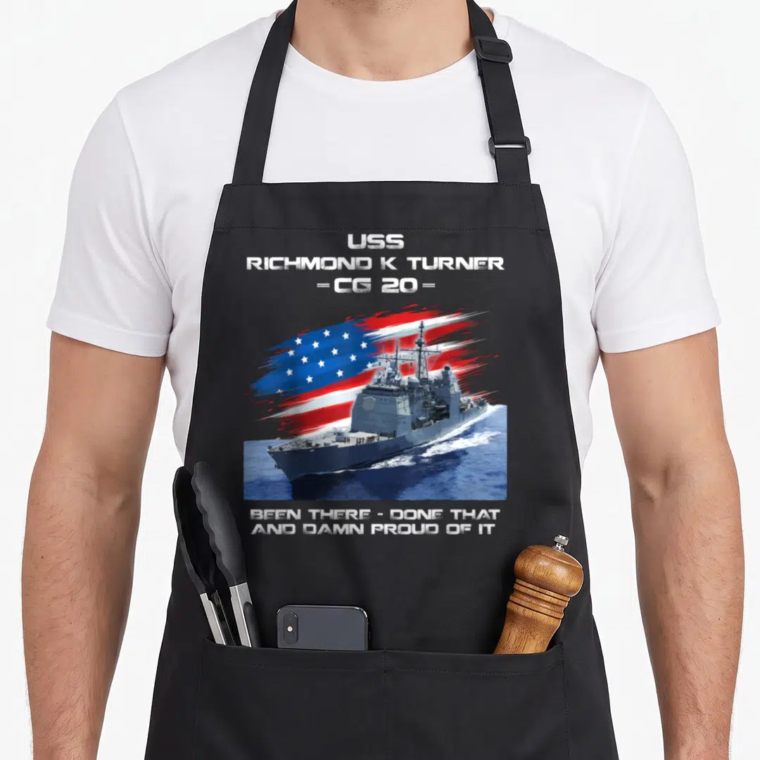 Turner american flag apron - USS Richmond K Turner CG 20 ship with flag and proud service text — shown on a black cotton canvas apron against a white background