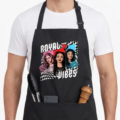 Royal novelty apron - Three women in pink red and blue panels with ROYAL VIBES text over checkerboard — shown on a black cotton canvas apron against a white background