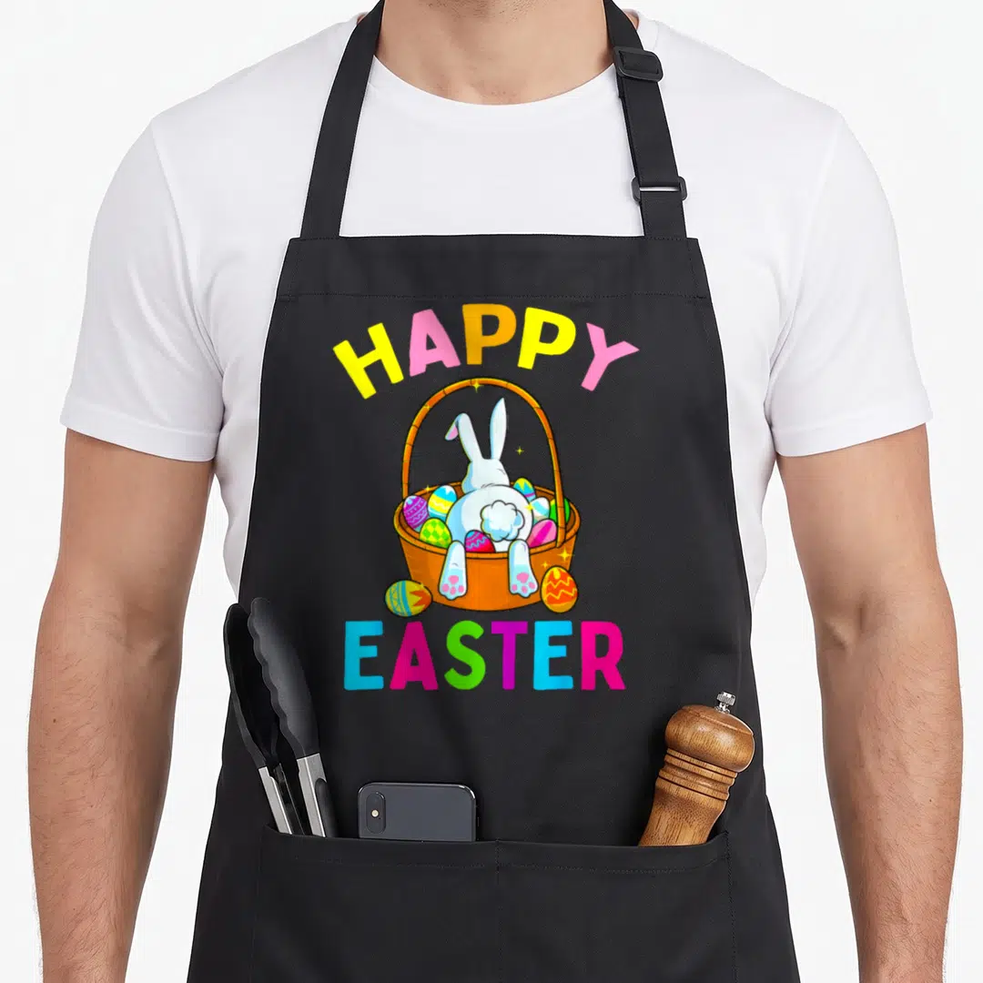 Hunting easter bunny aprons - Cartoon bunny diving into basket of eggs with happy easter text in pink yellow blue green — shown on a black cotton canvas apron against a white background