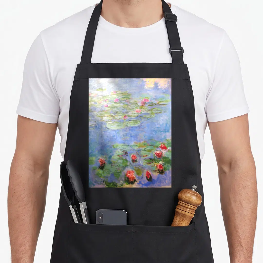 Claude white lily apron - Pink water lilies and green lily pads on blue water in watercolor style — shown on a black cotton canvas apron against a white background