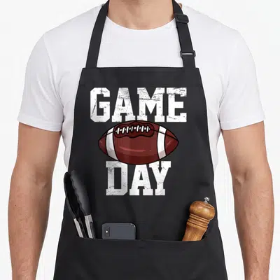 Player football apron - Brown football with white stripes between distressed white GAME and DAY text — shown on a black cotton canvas apron against a white background