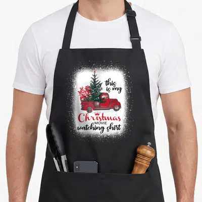 Movie red christmas apron - Red truck carrying Christmas tree and gifts with this is my Christmas MOVIE watching shirt — shown on a black cotton canvas apron against a white background