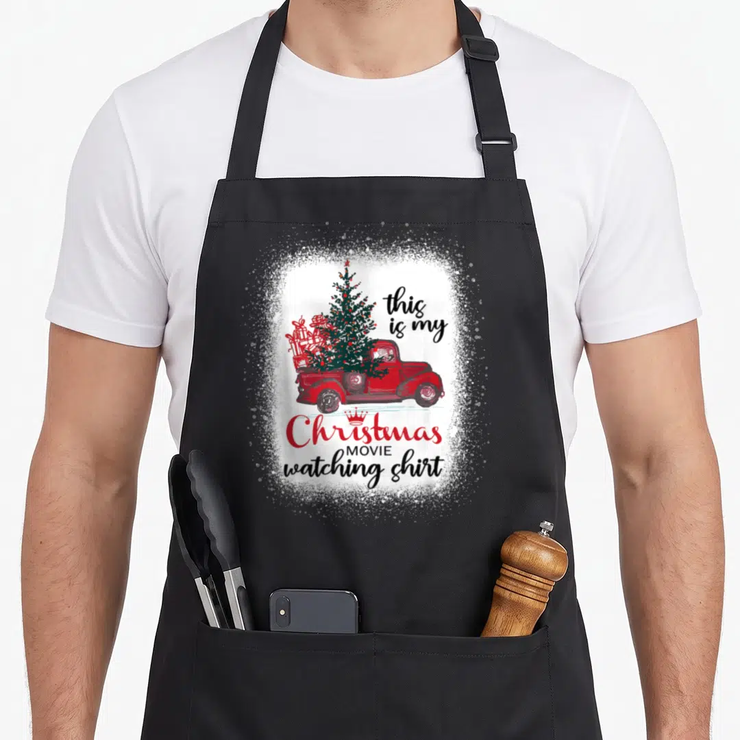 Movie red christmas apron - Red truck carrying Christmas tree and gifts with this is my Christmas MOVIE watching shirt — shown on a black cotton canvas apron against a white background