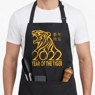 Tiger chinese zodiac apron - Yellow line art tiger forming 2022 with Chinese text and Year of the Tiger label — shown on a black cotton canvas apron against a white background