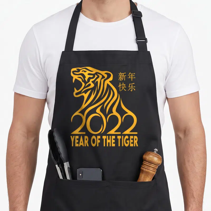 Tiger chinese zodiac apron - Yellow line art tiger forming 2022 with Chinese text and Year of the Tiger label — shown on a black cotton canvas apron against a white background