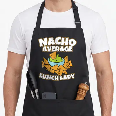 Lunch school cafeteria aprons - Nacho Average Lunch Lady text above guacamole bowl and tortilla chips in cartoon style — shown on a black cotton canvas apron against a white background