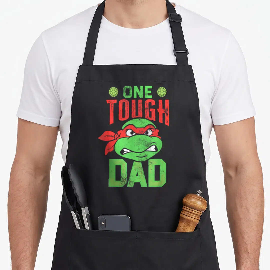 Tough father day apron - Green turtle head red bandana One Tough Dad distressed text — shown on a black cotton canvas apron against a white background