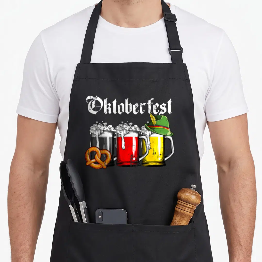 Beer german oktoberfest aprons - Three beer mugs in black red and yellow with a pretzel and green hat under arched — shown on a black cotton canvas apron against a white background