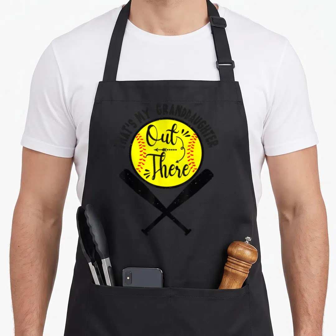Softball grandma granddaughter aprons - Yellow softball with red stitching, crossed bats, and arched text reading — shown on a black cotton canvas apron against a white background