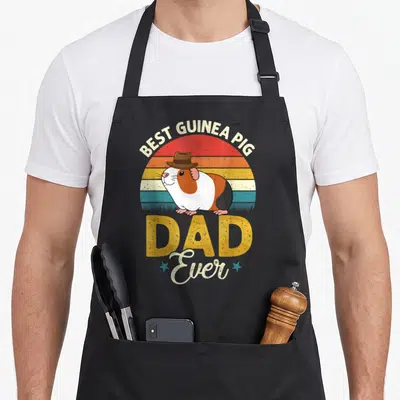 Owner guinea dad apron - Retro sun graphic with guinea pig in hat and text Best Guinea Pig Dad Ever — shown on a black cotton canvas apron against a white background