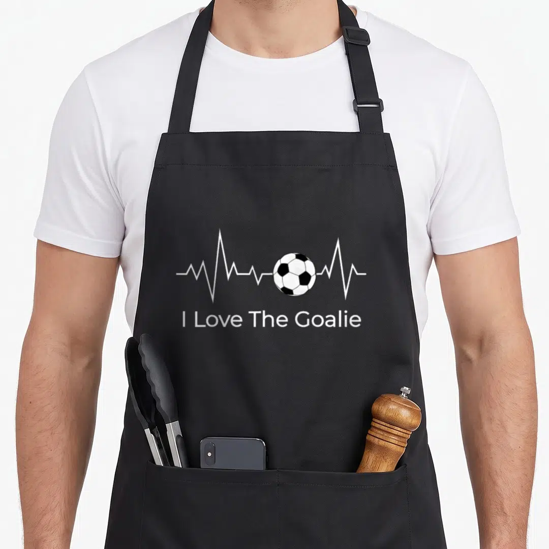 Soccer goalkeeper apron - I Love The Goalie text below a white heartbeat line with a black and white soccer ball — shown on a black cotton canvas apron against a white background