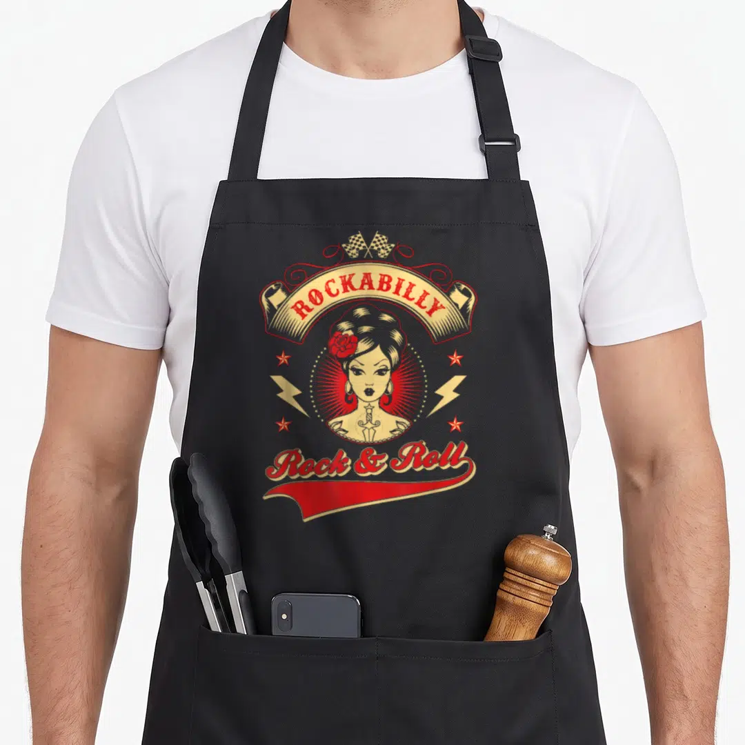 Elias rockabilly apron - Retro pin-up woman with red rose, ROCKABILLY banner, lightning bolts, and flags in red — shown on a black cotton canvas apron against a white background