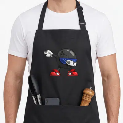 Dabbing world music apron - Cartoon black bowling ball character dabbing with blue sunglasses, white gloves, and red — shown on a black cotton canvas apron against a white background