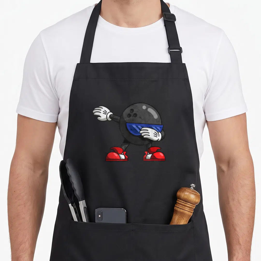 Dabbing world music apron - Cartoon black bowling ball character dabbing with blue sunglasses, white gloves, and red — shown on a black cotton canvas apron against a white background