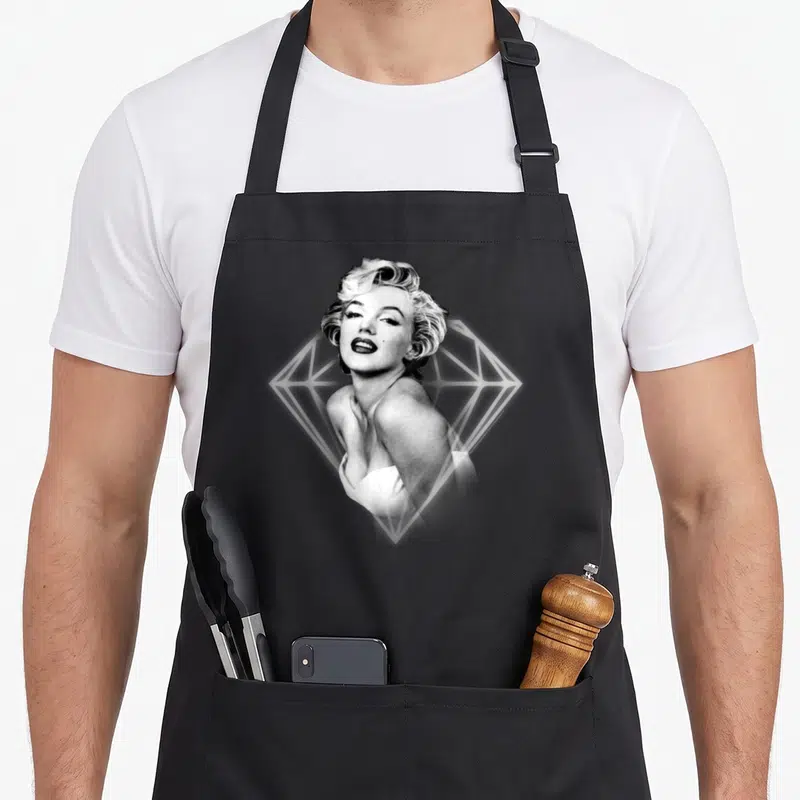 Glowing marilyn monroe apron - Black and white woman photo over white diamond line art — shown on a black cotton canvas apron against a white background