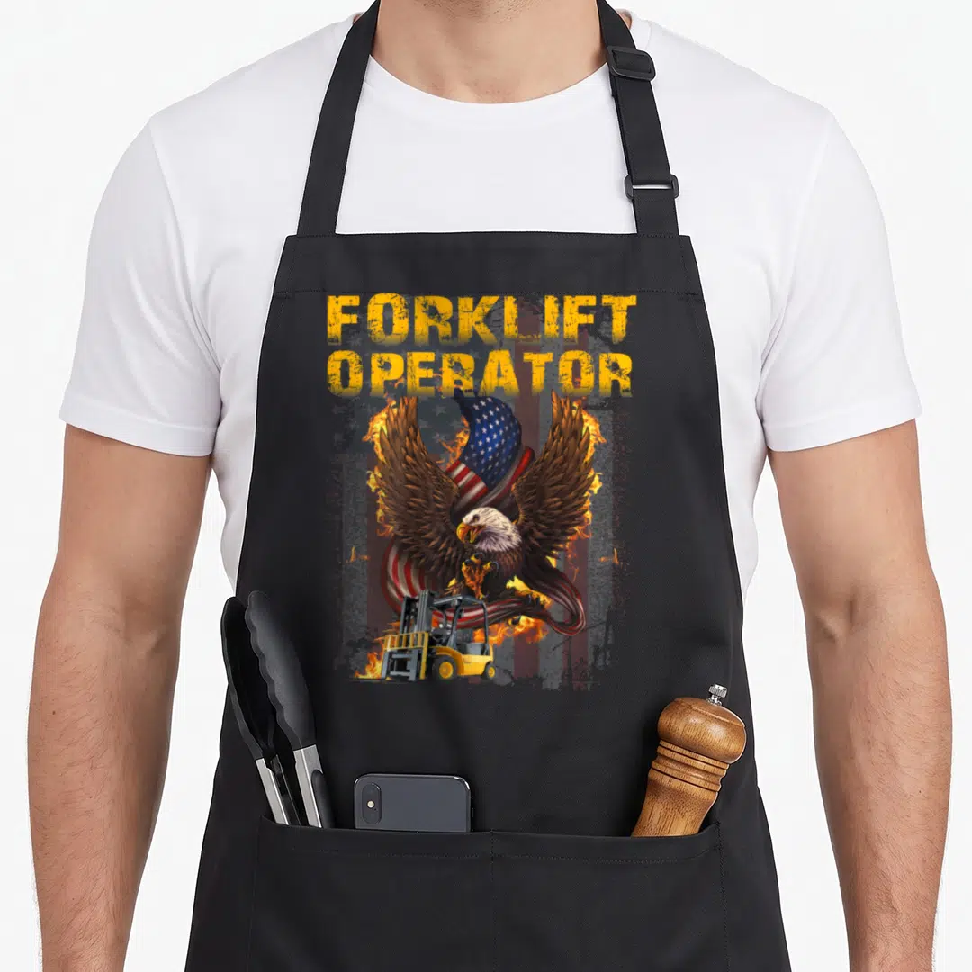 Proud forklift apron - Eagle with spread wings, USA flag, fire, and yellow FORKLIFT OPERATOR text above a truck — shown on a black cotton canvas apron against a white background