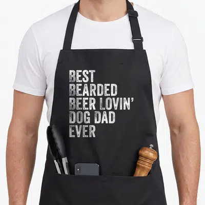 Bearded custom pet apron - White stacked text reading BEST BEARDED BEER LOVIN DOG DAD EVER — shown on a black cotton canvas apron against a white background