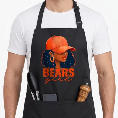 Funny sport bear apron - Cartoon woman in orange cap with BEARS girl text in navy and brown — shown on a black cotton canvas apron against a white background