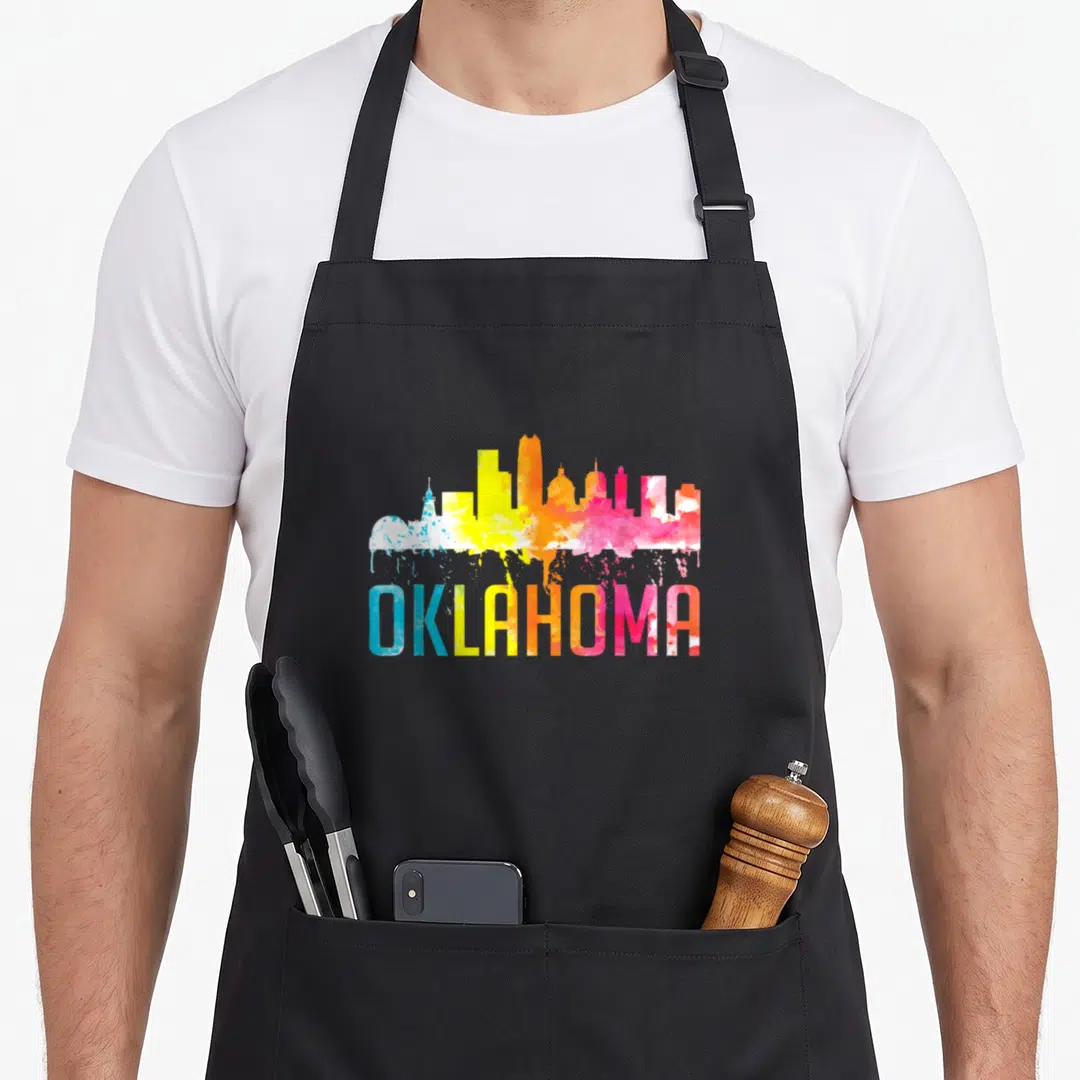 Oklahoma skyline art apron - Colorful watercolor Oklahoma skyline with paint drips and gradient text — shown on a black cotton canvas apron against a white background