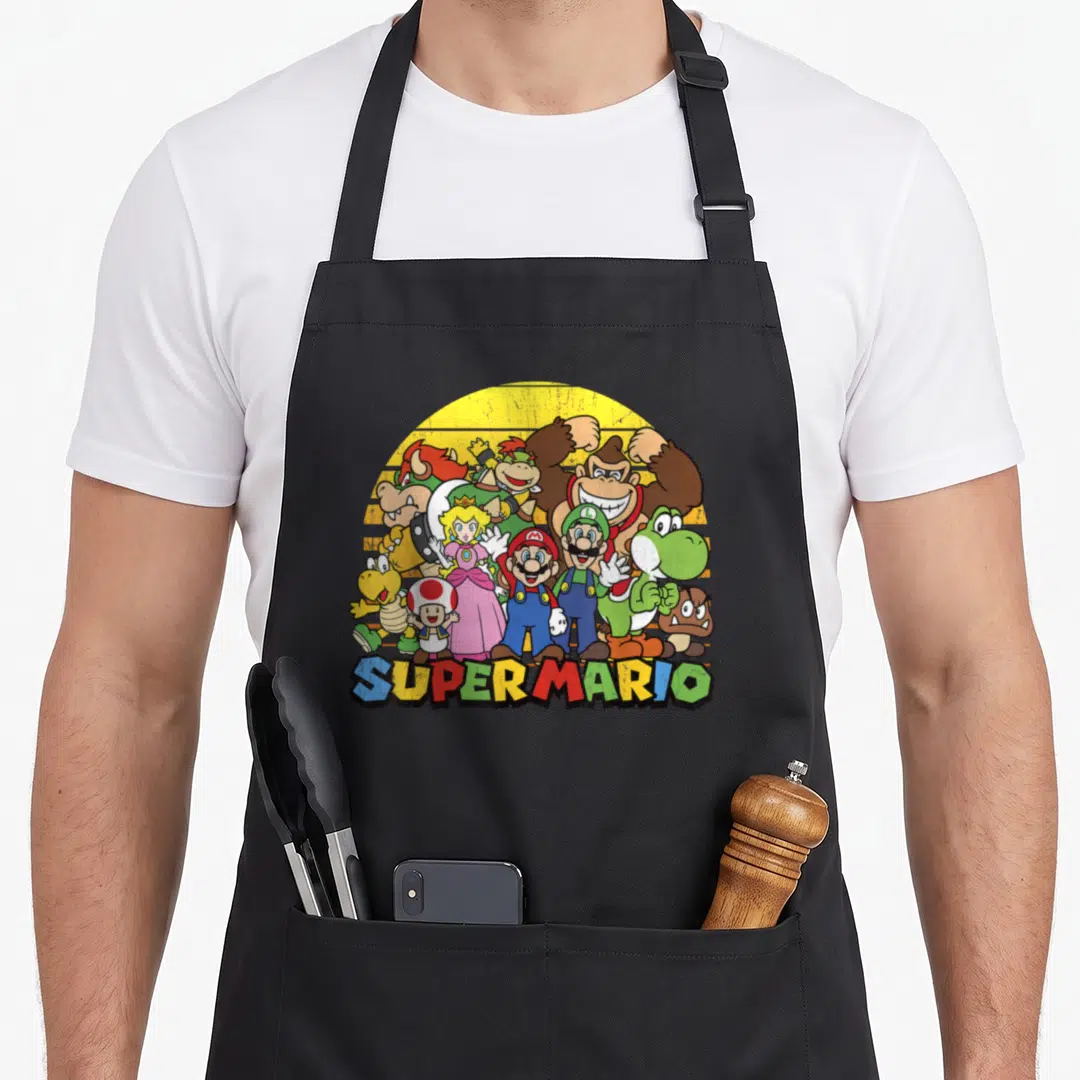 Portrait novelty apron - Super Mario characters clustered before yellow sun with colorful text at bottom — shown on a black cotton canvas apron against a white background