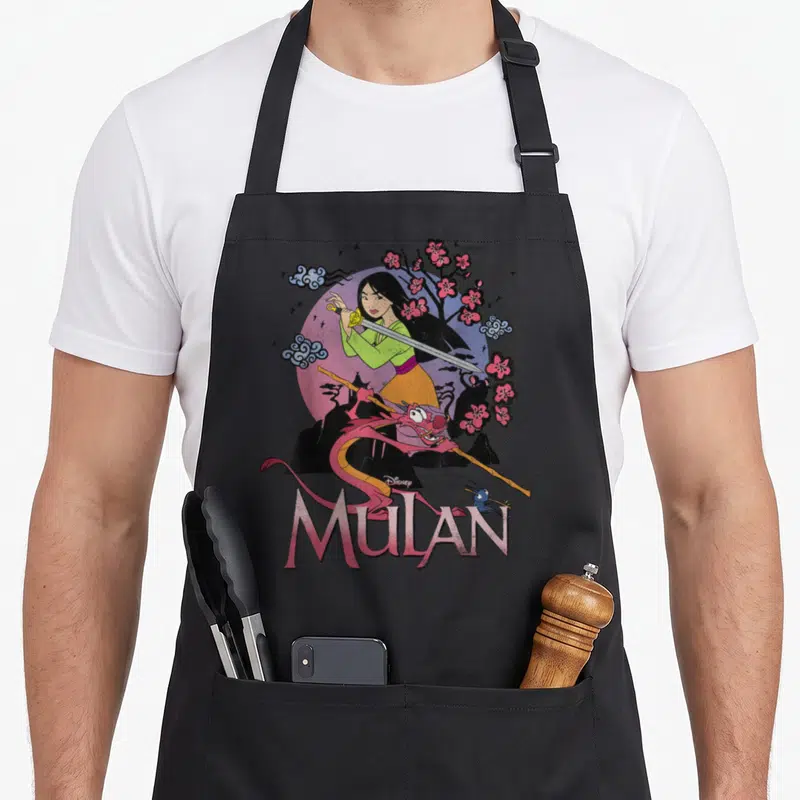 Stance warrior apron - Mulan holding sword with Mushu Cri-Kee pink sun cherry blossoms cartoon art — shown on a black cotton canvas apron against a white background