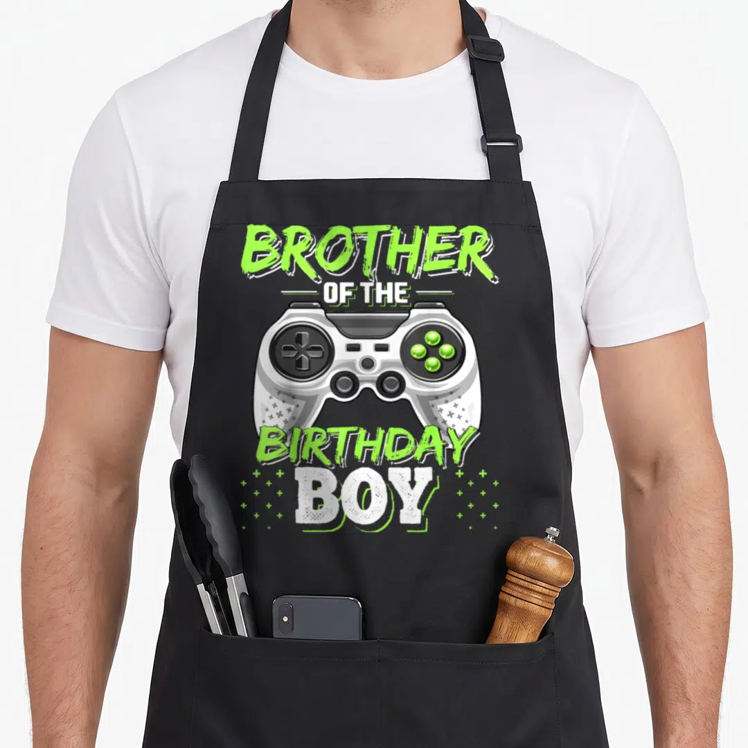 Brother video game apron - Lime green controller graphic with Brother of the Birthday Boy text and scattered plus signs — shown on a black cotton canvas apron against a white background