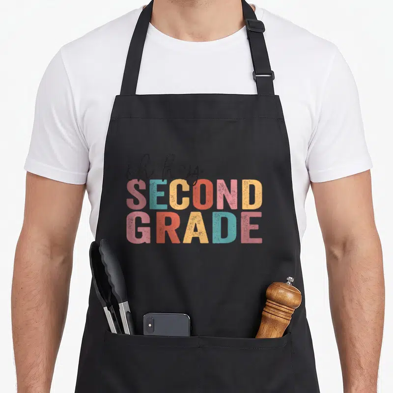 Second grade teacher apron - Stacked oh hey SECOND GRADE text in pink teal yellow and red block letters — shown on a black cotton canvas apron against a white background