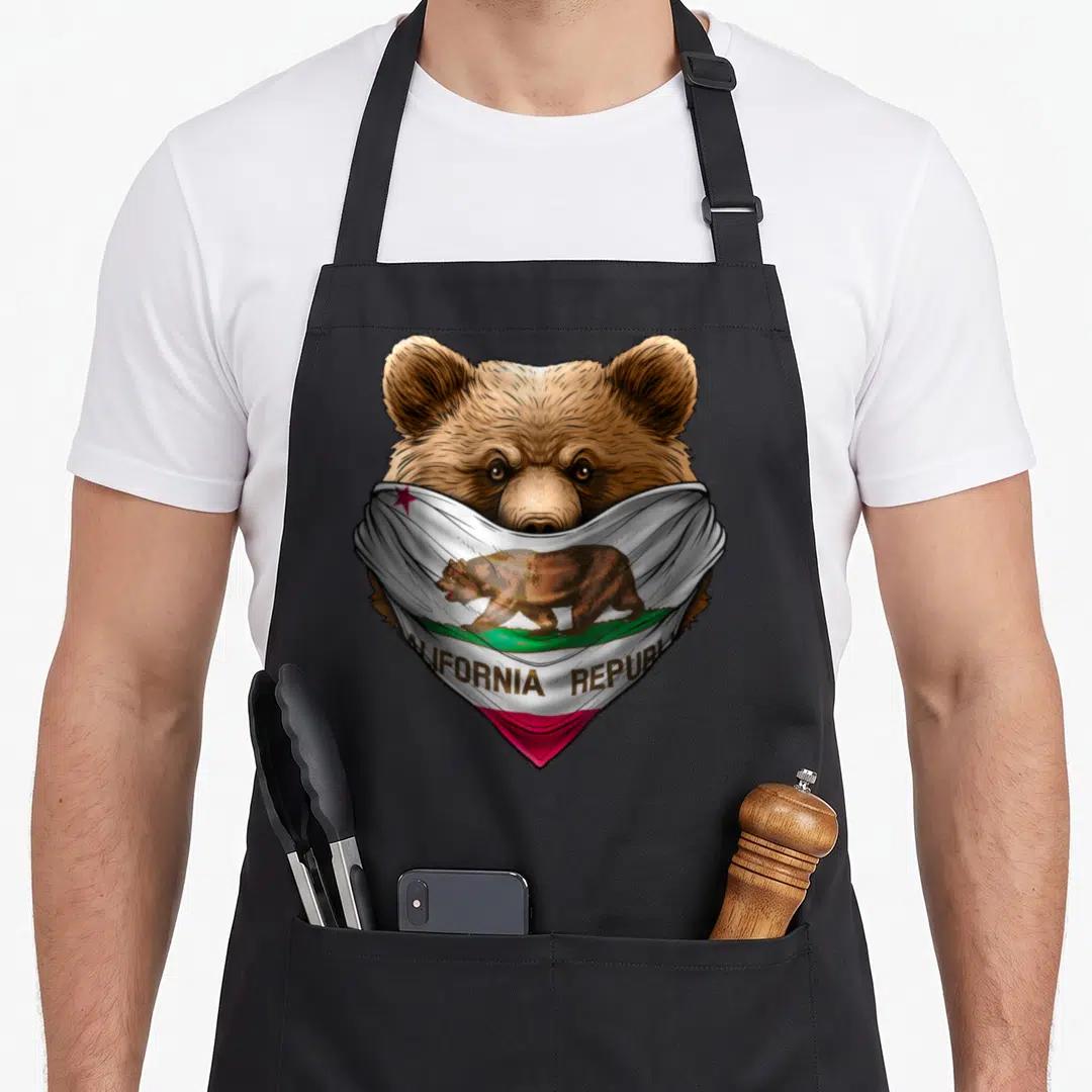 Bandana bear apron - Realistic brown bear wearing a white California Republic flag bandana with text — shown on a black cotton canvas apron against a white background