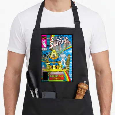 Surfer rainbow apron - Thanos on gold throne with Silver Surfer under rainbow and Marvel comic text — shown on a black cotton canvas apron against a white background