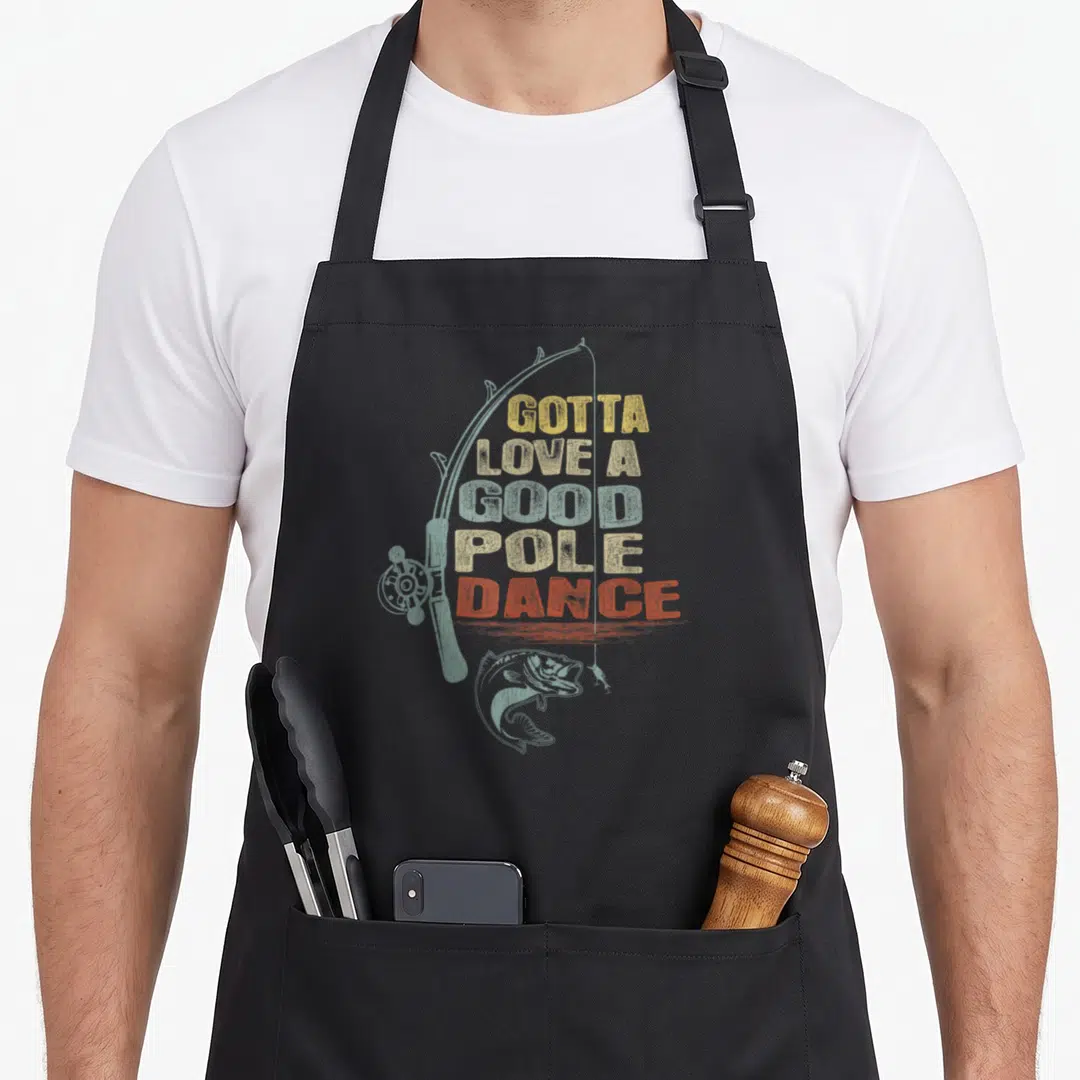 Pole fishing aprons - GOTTA LOVE A GOOD POLE DANCE text over fishing rod and bass illustration in distressed colors — shown on a black cotton canvas apron against a white background