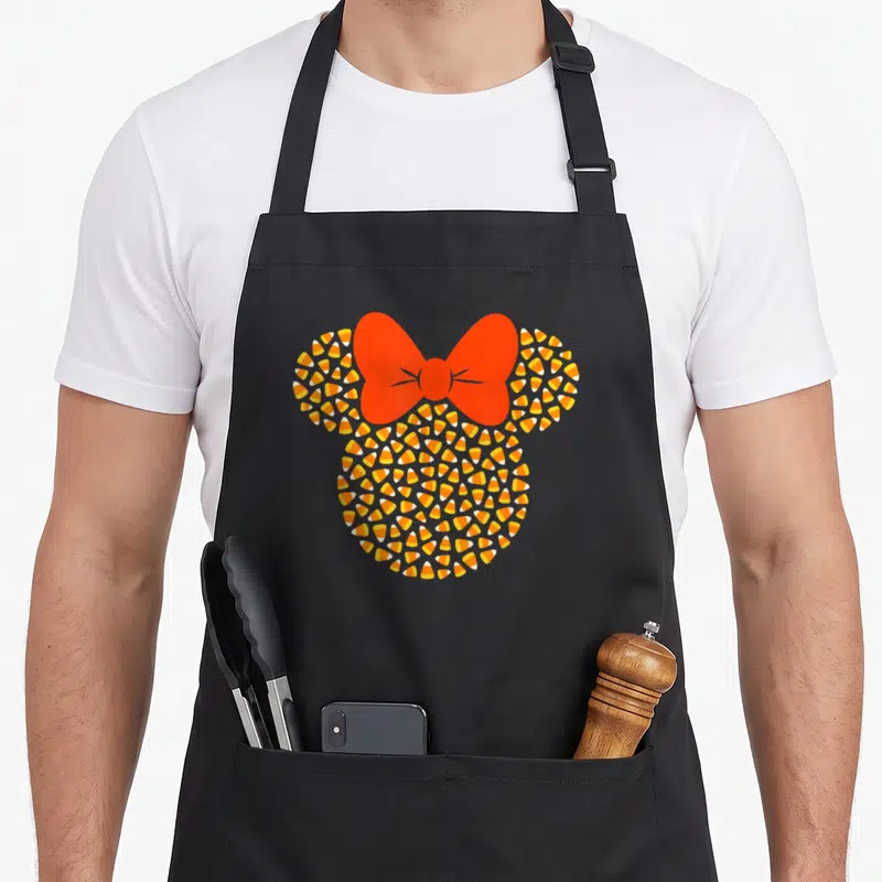 Candy halloween apron - Mouse head silhouette made of candy corn with red bow in orange and yellow — shown on a black cotton canvas apron against a white background