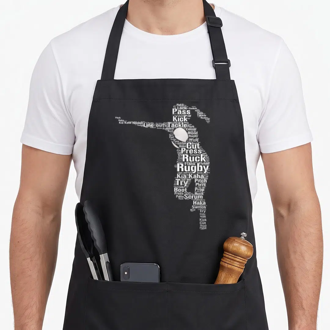 Funny player rugby apron - White word cloud silhouette of a rugby player formed by terms like tackle, ruck, and haka — shown on a black cotton canvas apron against a white background