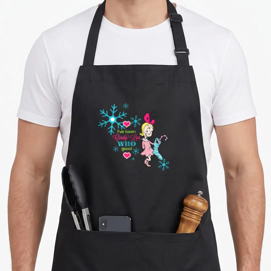 Funny cindy lou who apron - Cindy-Lou Who holding striped stocking next to I've been Cindy-Lou WHO good text — shown on a black cotton canvas apron against a white background