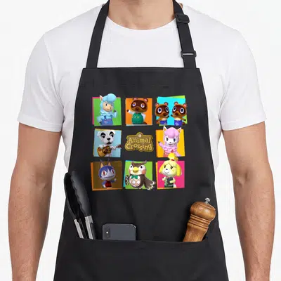 Shot animal apron - Grid of cartoon characters in blue green orange pink yellow squares with Welcome to Animal Crossing — shown on a black cotton canvas apron against a white background