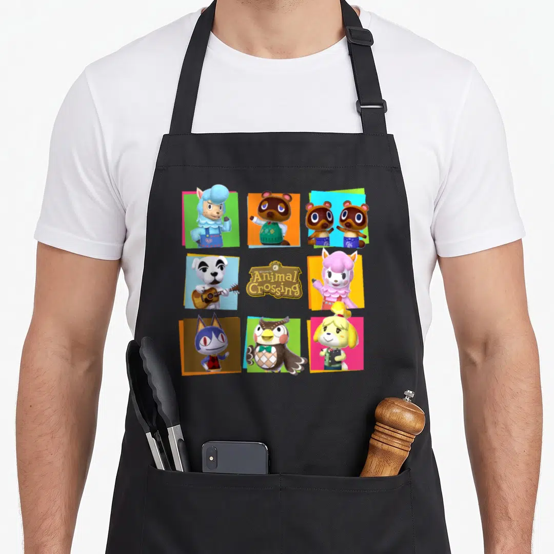 Shot animal apron - Grid of cartoon characters in blue green orange pink yellow squares with Welcome to Animal Crossing — shown on a black cotton canvas apron against a white background