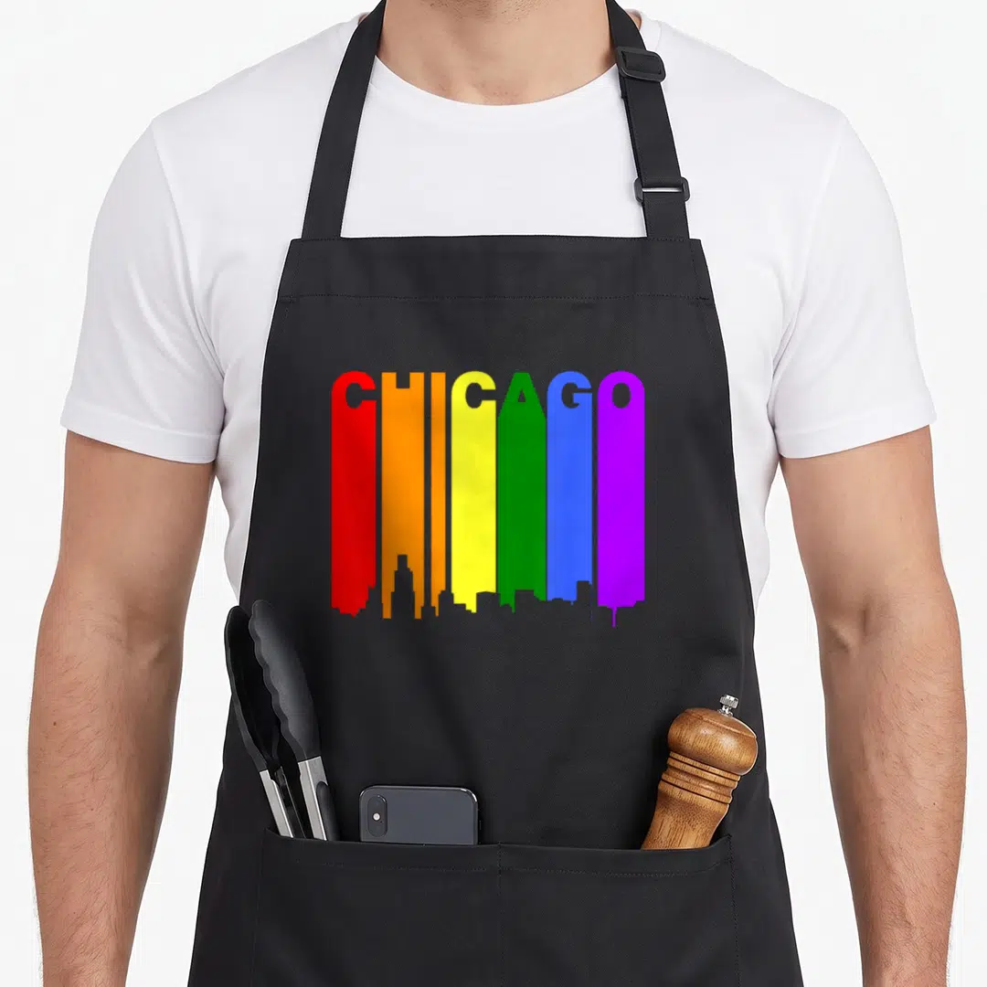 Chicago gay pride apron - CHICAGO in rainbow letters forming skyline silhouette with red orange yellow green blue purple — shown on a black cotton canvas apron against a white background