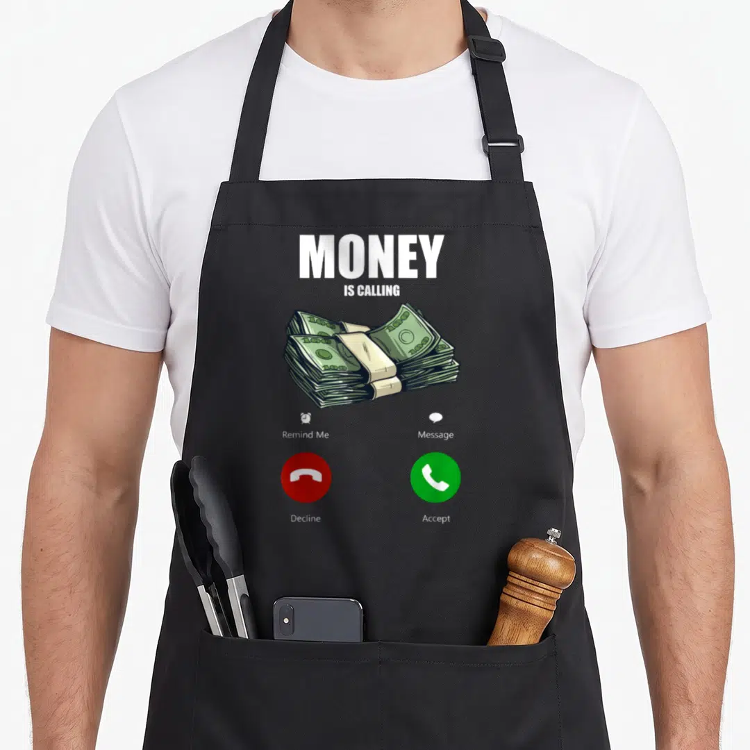 Calling money apron - MONEY IS CALLING text, cash stack, red decline green accept buttons — shown on a black cotton canvas apron against a white background