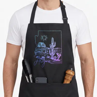 Arizona state cactus apron - Line art saguaro and mesa inside Arizona state outline in blue and purple — shown on a black cotton canvas apron against a white background