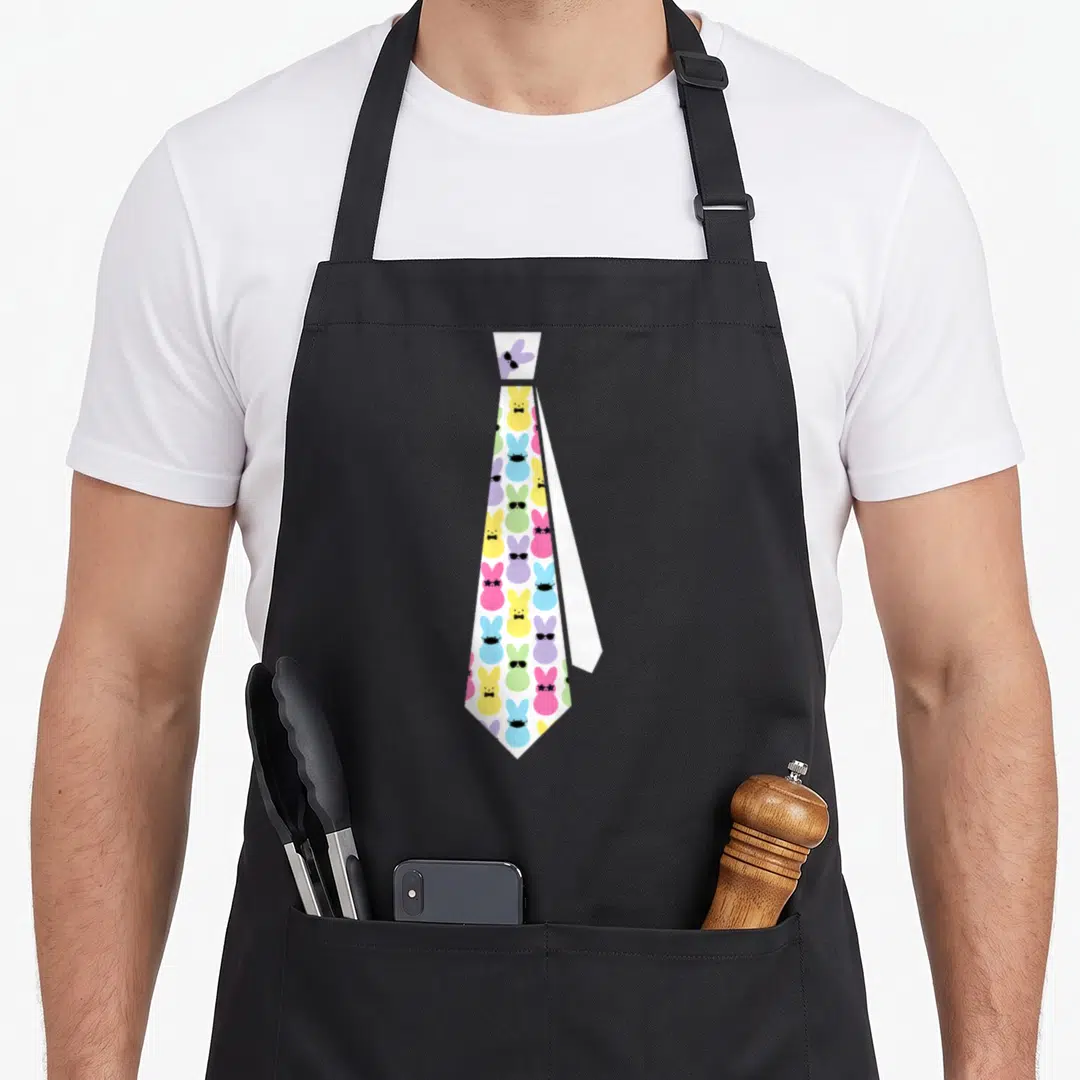 Tie easter bunny aprons - White necktie graphic with colorful cartoon bunnies wearing sunglasses and bowties — shown on a black cotton canvas apron against a white background