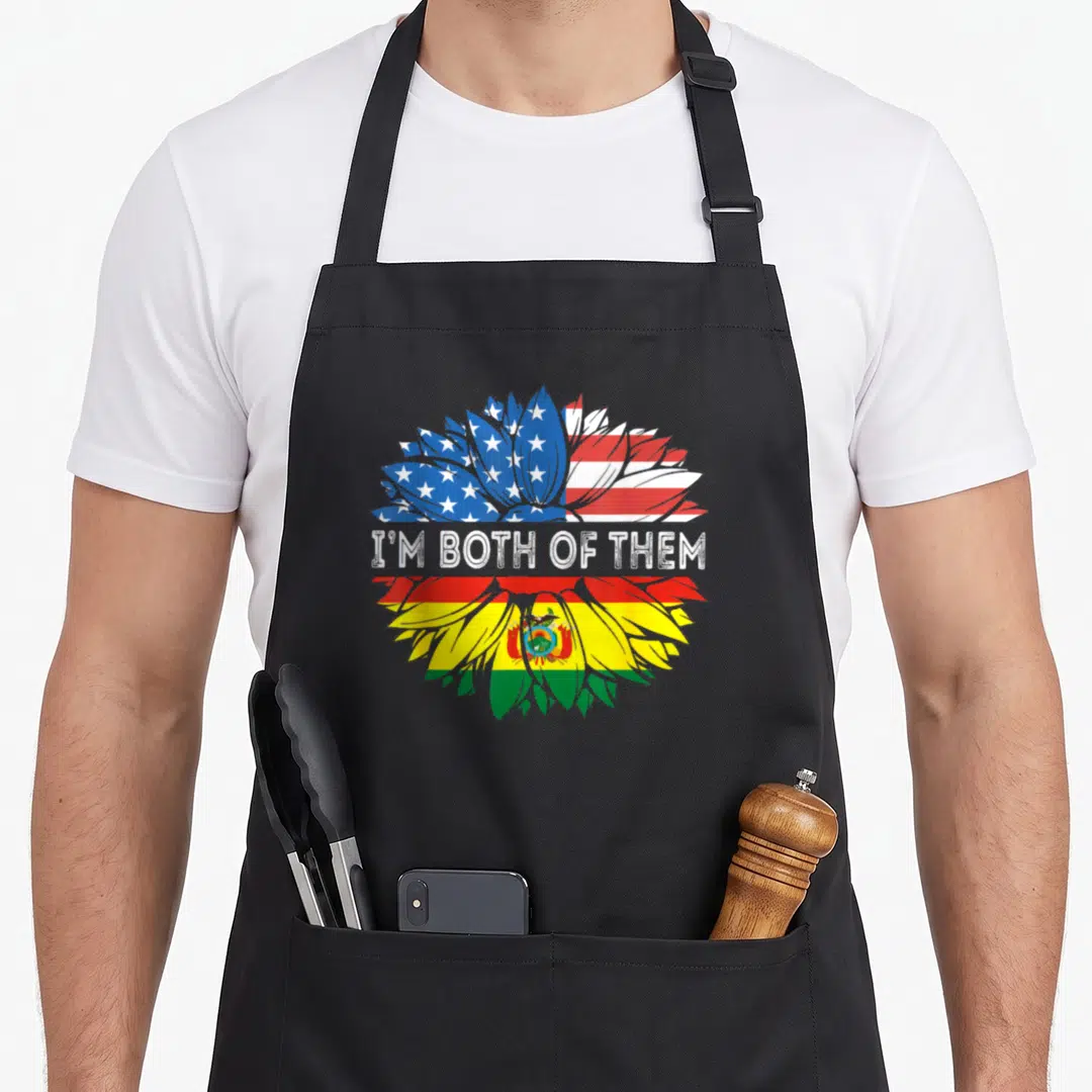 Bolivia sunflower apron - Split flower with USA and Bolivian flags and I'M BOTH OF THEM text — shown on a black cotton canvas apron against a white background
