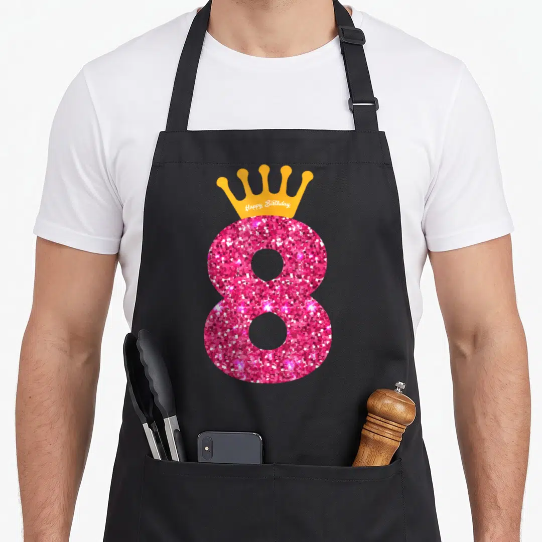 8th bday birthday apron - Pink glittery number 8 with orange crown containing white Happy Birthday text — shown on a black cotton canvas apron against a white background