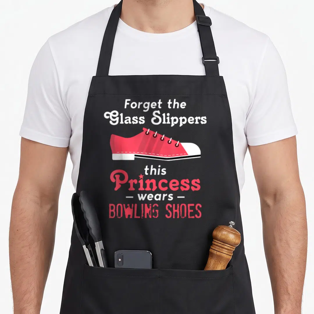 Funny bowling wife apron - Cartoon pink bowling shoe with text forget glass slippers princess wears bowling shoes — shown on a black cotton canvas apron against a white background
