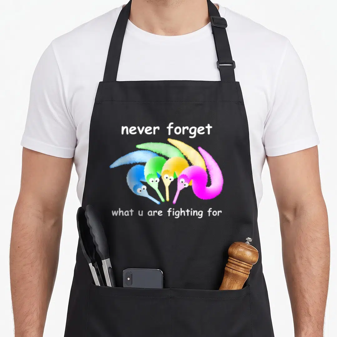 Forget magic apron - Four fuzzy pipe cleaner worms in blue green yellow and pink under white text — shown on a black cotton canvas apron against a white background