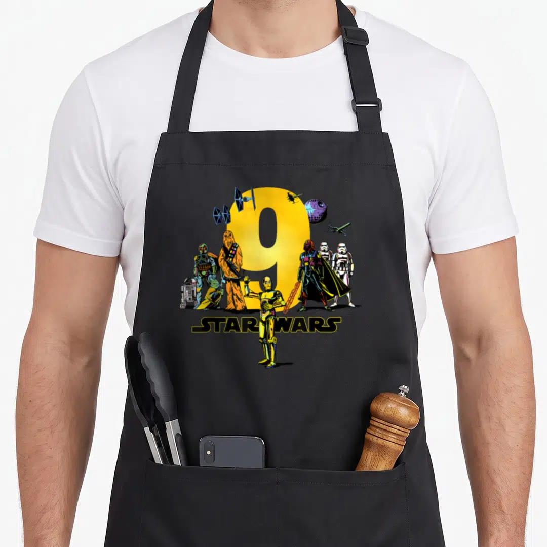 Character ninth birthday apron - Yellow number 9 surrounded by Star Wars cartoon characters and logo — shown on a black cotton canvas apron against a white background