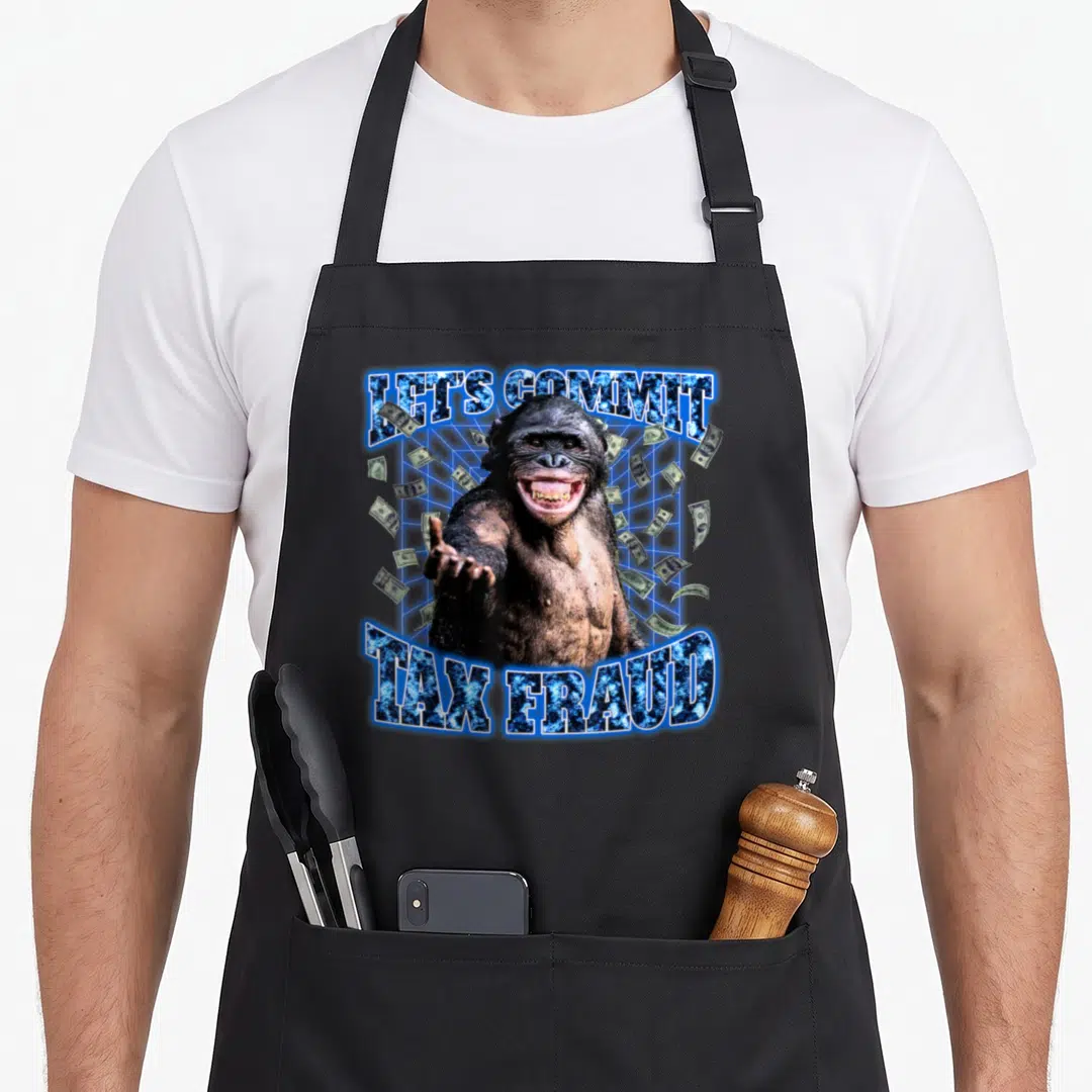 Commit 90s apron - Chimpanzee photo with Let's Commit Tax Fraud text and floating banknotes on blue grid — shown on a black cotton canvas apron against a white background