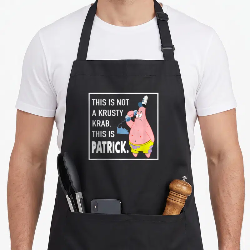 Funny krusty krab apron - Patrick Star holding blue phone next to white text reading THIS IS NOT A KRUSTY KRAB THIS IS — shown on a black cotton canvas apron against a white background