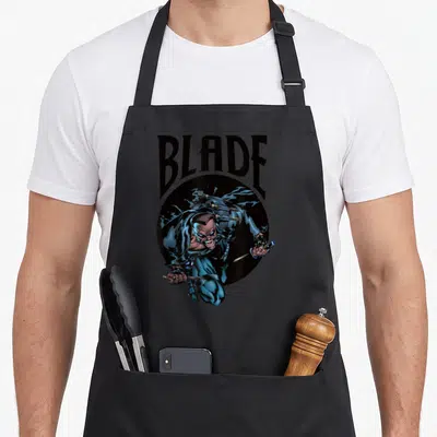 Vampire hunter apron - Blade character lunging with daggers under arched text on black circle — shown on a black cotton canvas apron against a white background